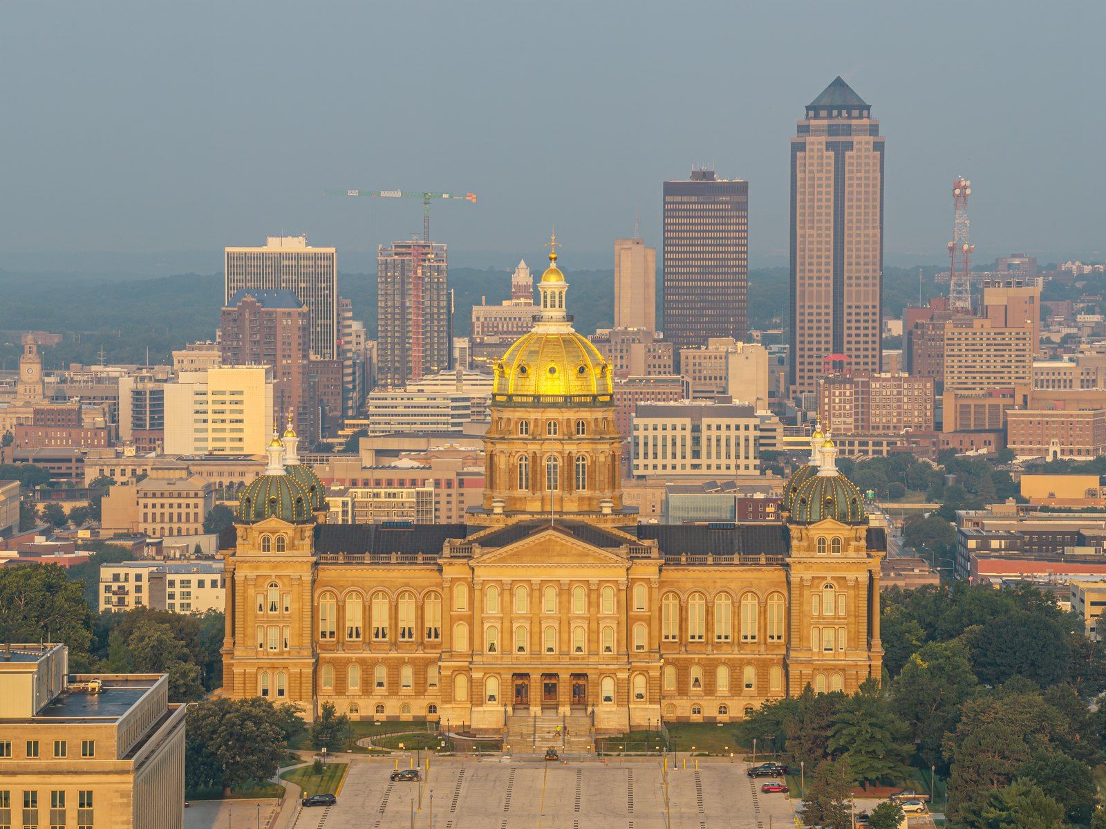 The gold dome of the Iowa State Capitol with the downtown Des Moines skyline behind it at sunrise